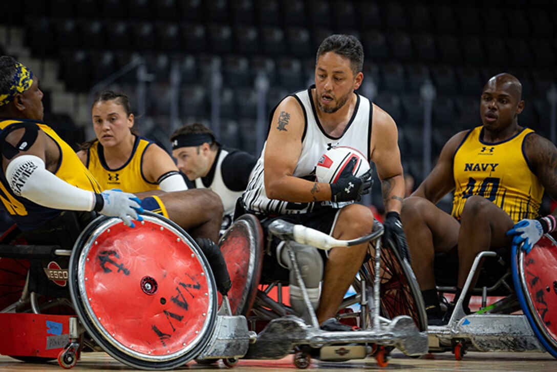 U.S. Army Retired Spc. Anthony Farve takes the ball down the court during a wheelchair rugby match against Team Navy at the 2025 Department of Defense Warrior Games in Colorado Springs Colorado, July 22, 2025.