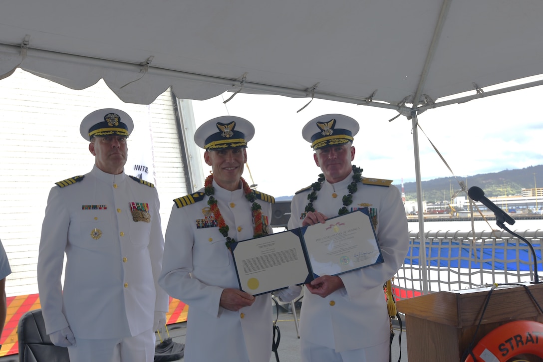 Rear Adm. Jeffrey Novak, deputy commander of Coast Guard Pacific Area and commander of the Coast Guard Southwest District, (right) presents Capt. Brian Krautler with an award on U.S. Coast Guard Cutter Stratton during a change of command ceremony while moored at Base Honolulu, July 22, 2025. Krautler served as Stratton’s commanding officer from April 2023 to July 2025. (U.S. Coast Guard photo by Ensign Sarah Choe)
