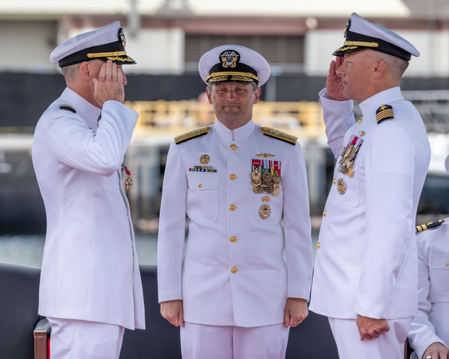 JOINT BASE PEARL HARBOR-HICKAM, Hawaii (July 25, 2025) - Capt. Jeff Fassbender, right, salutes Capt. Corey Poorman, left, as Rear Adm. Chris Cavanaugh, commander, Submarine Force, U.S. Pacific Fleet, center, observes during the Commander, Submarine Squadron 7 change of command ceremony aboard the Los Angeles-class fast-attack submarine USS Columbia (SSN 771), July 25, 2025. During the ceremony, Fassbender, from St. Marys, Kansas, relieved Poorman, from Severna Park, Maryland, as CSS 7 commodore. (U.S. Navy photo by Mass Communication Specialist 1st Class Scott Barnes)