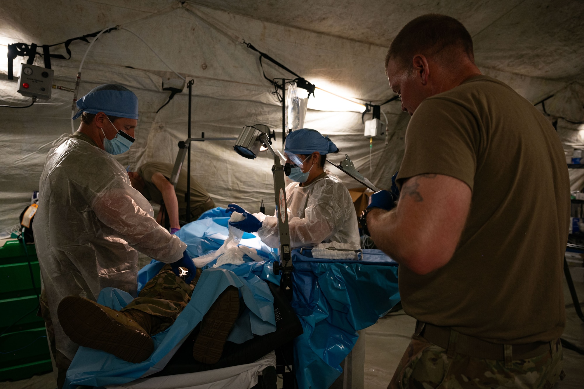 Photo of an orthopedic surgeon and his team performing a simulated surgery on a mock casualty's leg