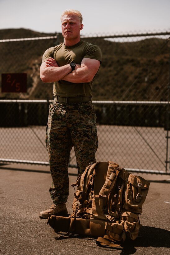 A U.S. Marine with 1st Battalion, 5th Marine Regiment, poses for a photo while standing next to a new main pack frame during a limited user evaluation at Marine Corps Base Camp Pendleton, Calif.