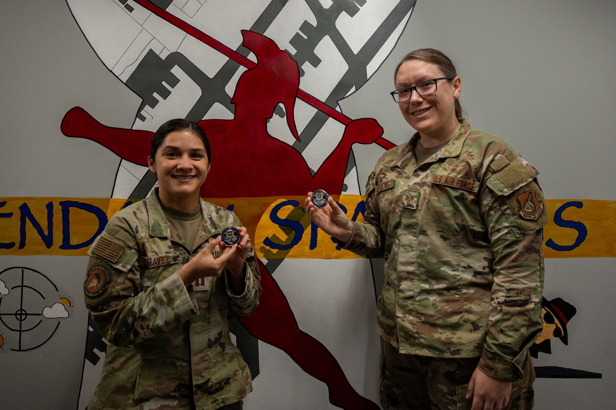 Photo of two Airmen posing after receiving coins from a commander
