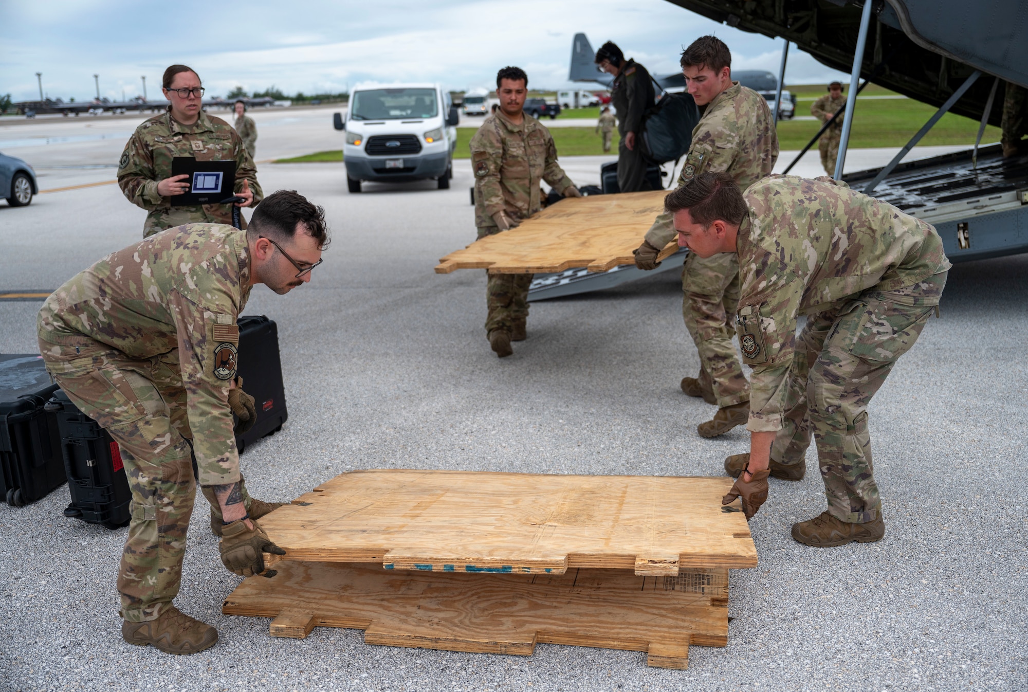 Multiple Airmen are seen moving gear out of the cargo bay of a C-130J Hercules.