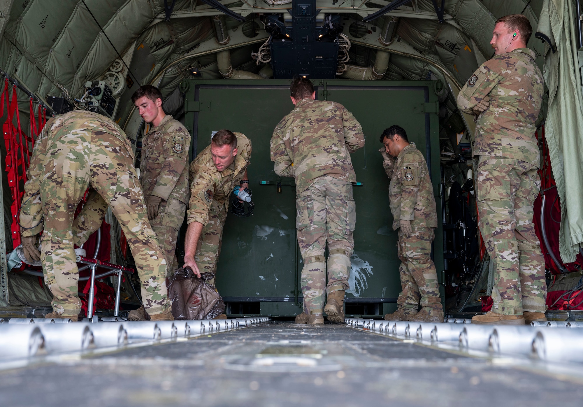 In the cargo bay of a C-130J Hercules, a group of Airmen prepare the bay after landing at Andersen Air Force Base, Guam.