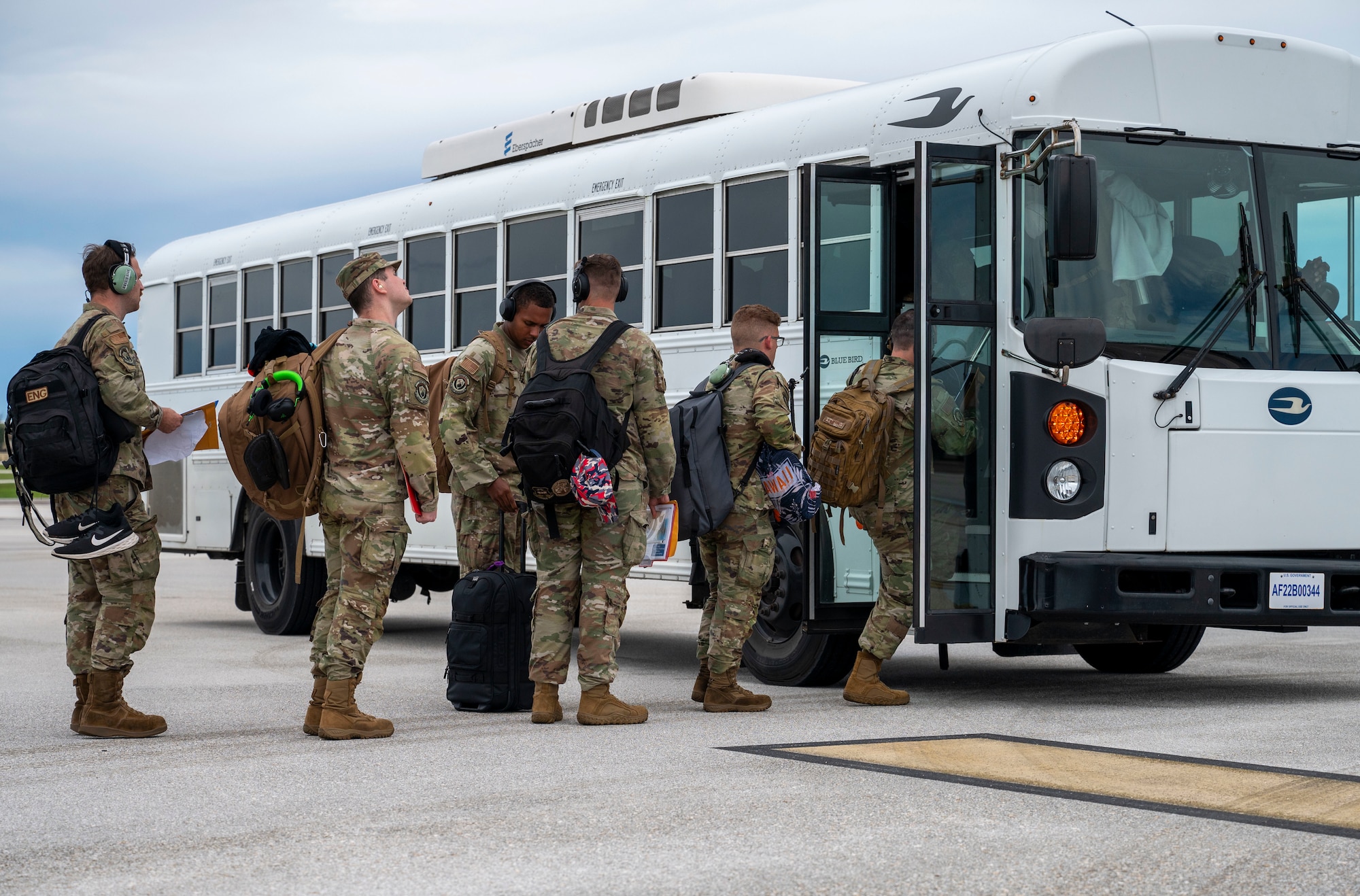 On a cloudy day, a group of Airmen board a shuttle after landing at Andersen Air Force Base, Guam.
