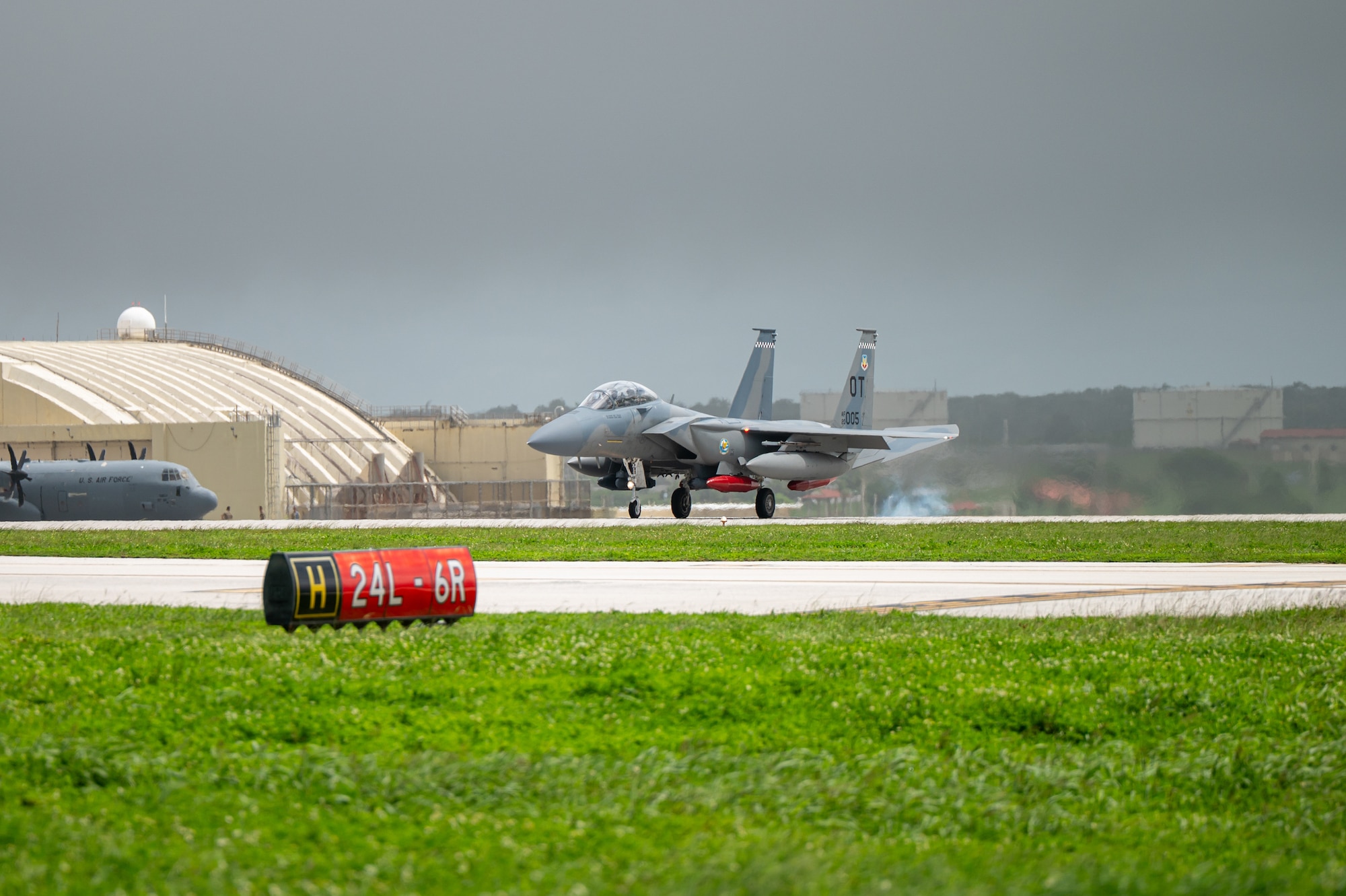 A U.S. Air Force F-15EX Eagle II lands at Andersen Air Force Base, Guam. You can see smoke and a heat mirage behind the aircraft.