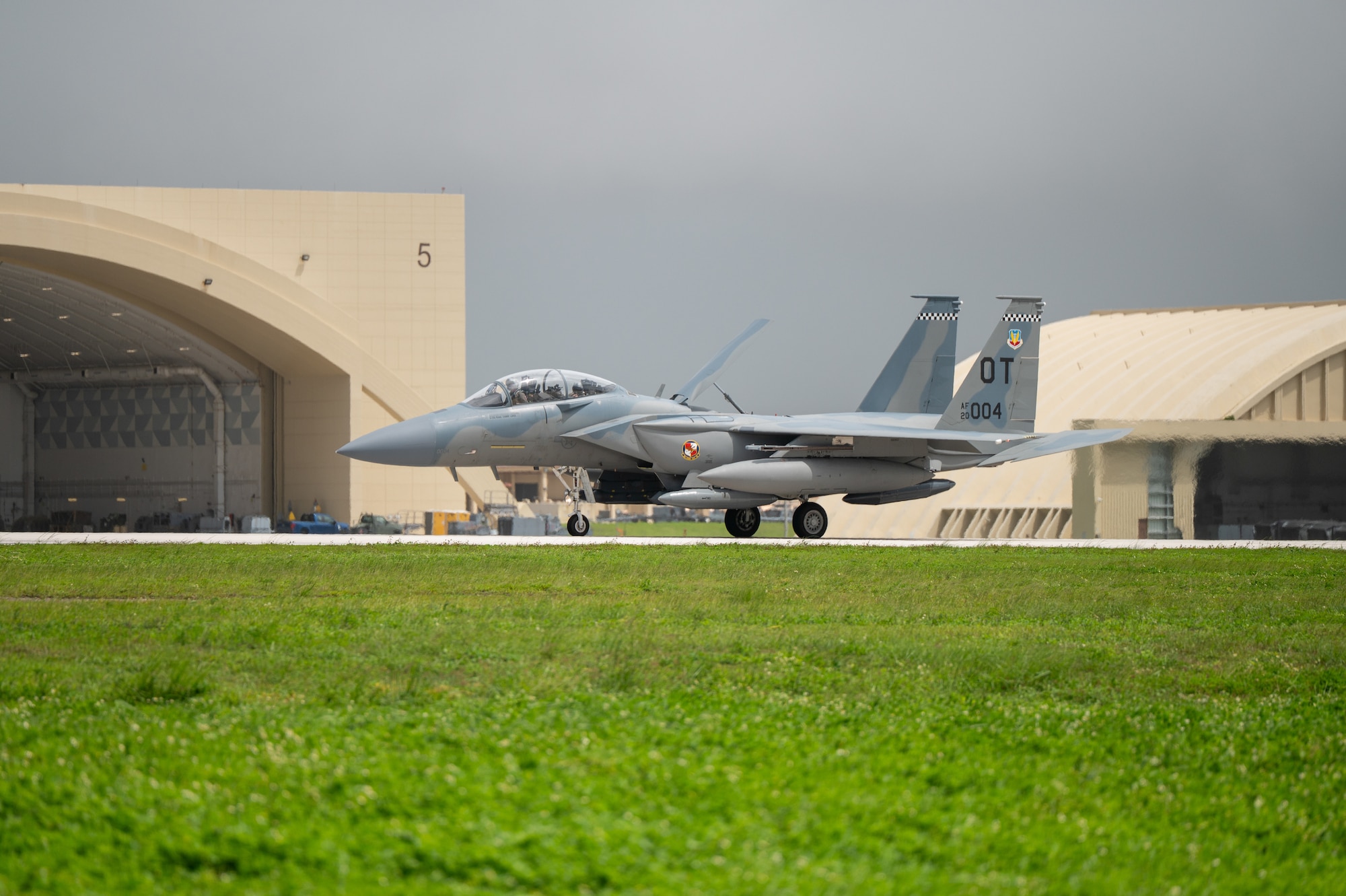 A U.S. Air Force F-15EX Eagle II lands on a runway. You can see the heat mirage behind the aircraft as it moves.