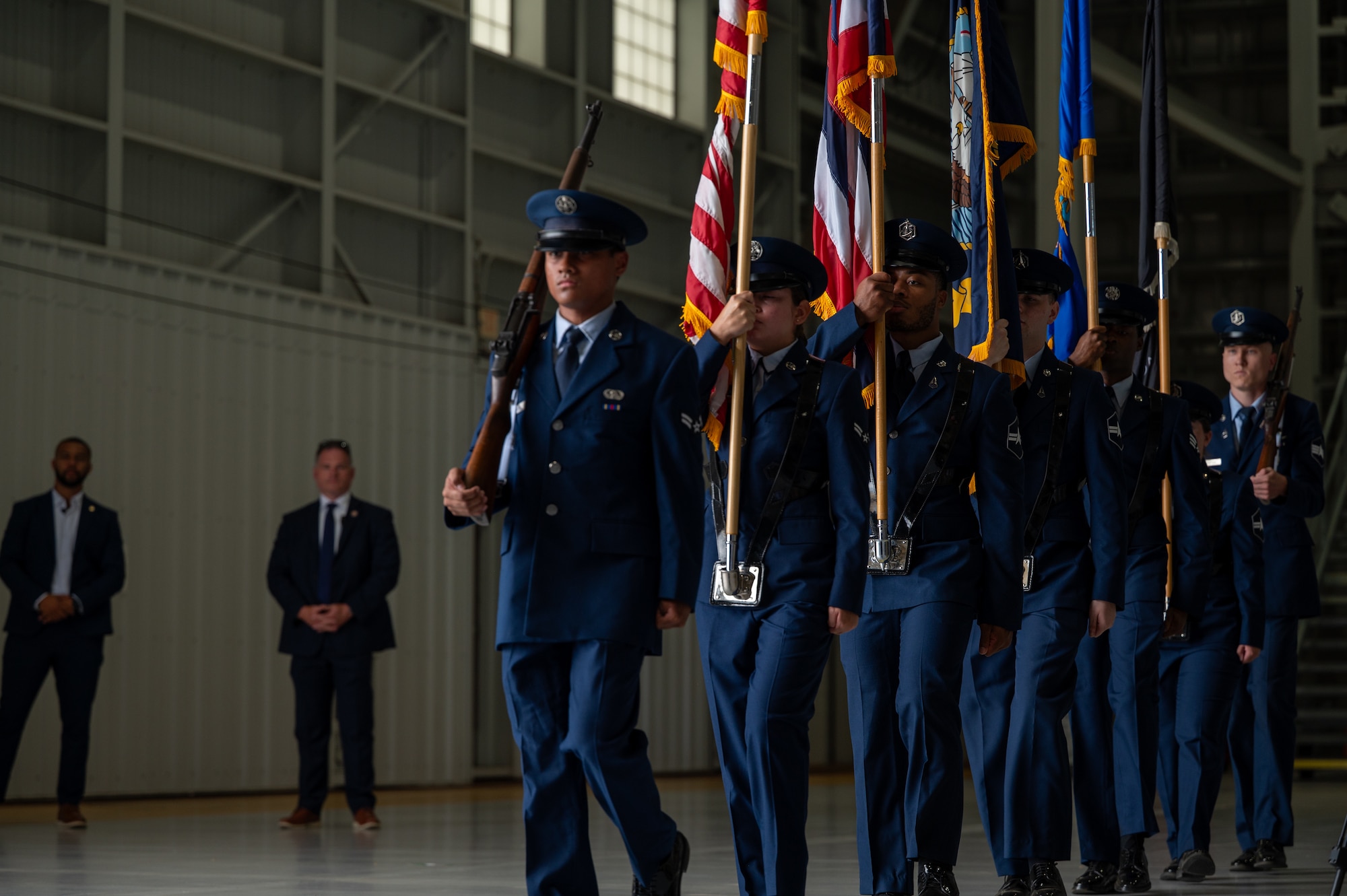 Men and women in uniform march with flags