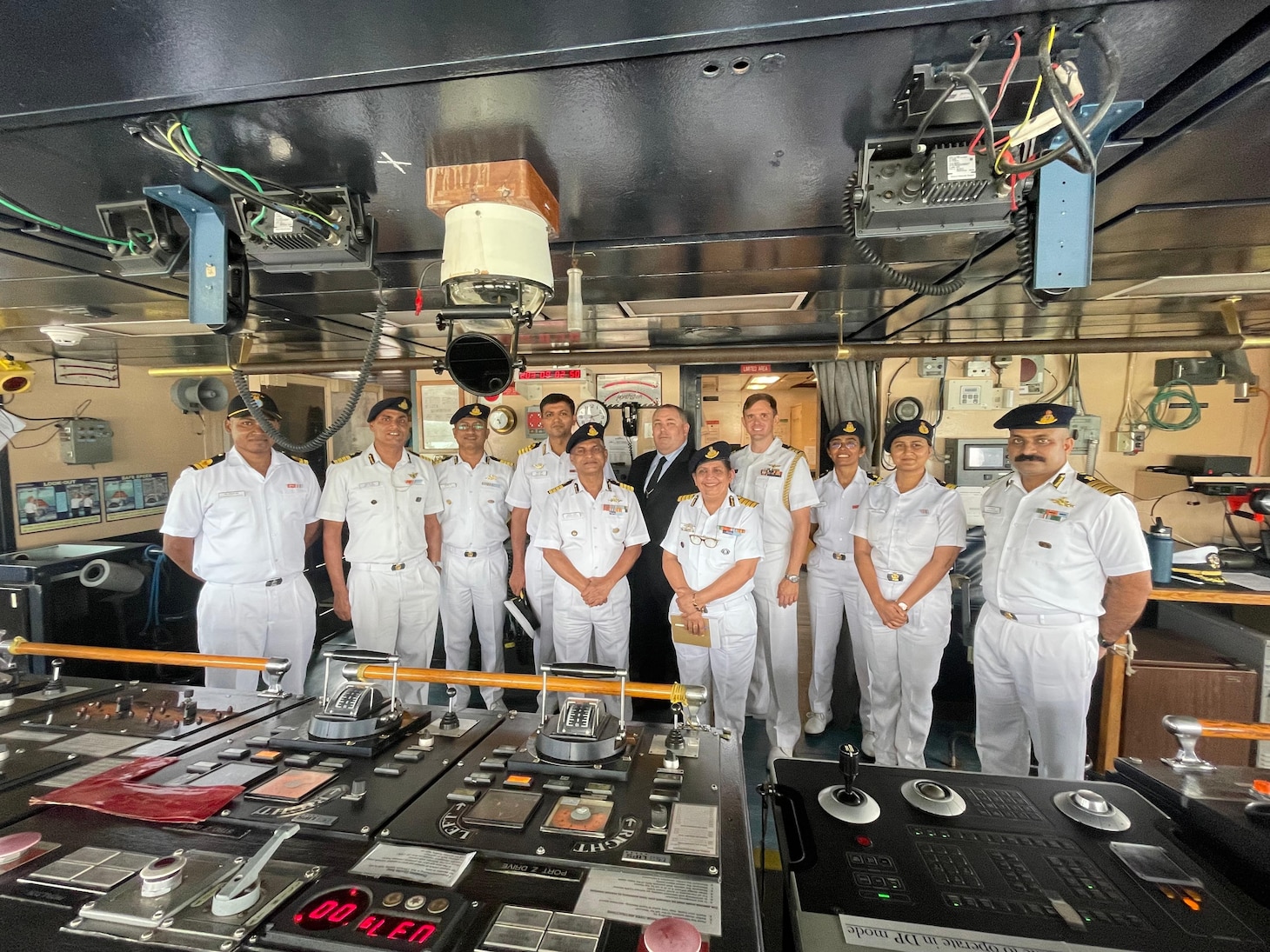 David Mitchell, center, Captain of pathfinder class oceanographic survey ship USNS Bowditch (T-AGS 62), poses with Indian Navy and Indian Coast Guard personnel in the bridge of the USNS Bowditch during a scheduled port visit to Sri Vijaya Puram, India, July 25, 2025.