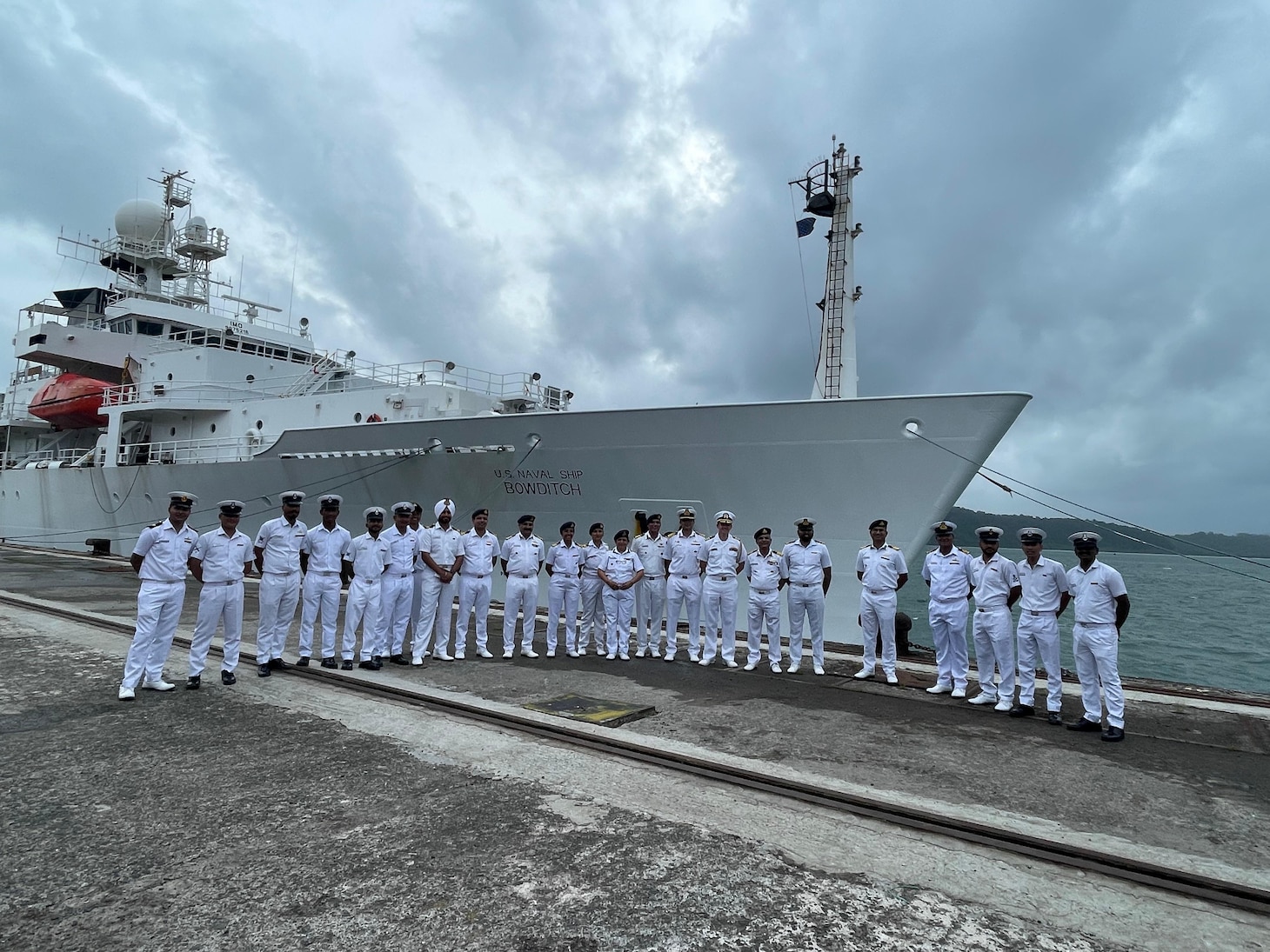 Indian Navy and Indian Coast Guard personnel alongside U.S. Navy sailors pose for a photo in front of the pathfinder class oceanographic survey ship USNS Bowditch (T-AGS 62) during a scheduled port visit to Sri Vijaya Puram, India, July 25, 2025.