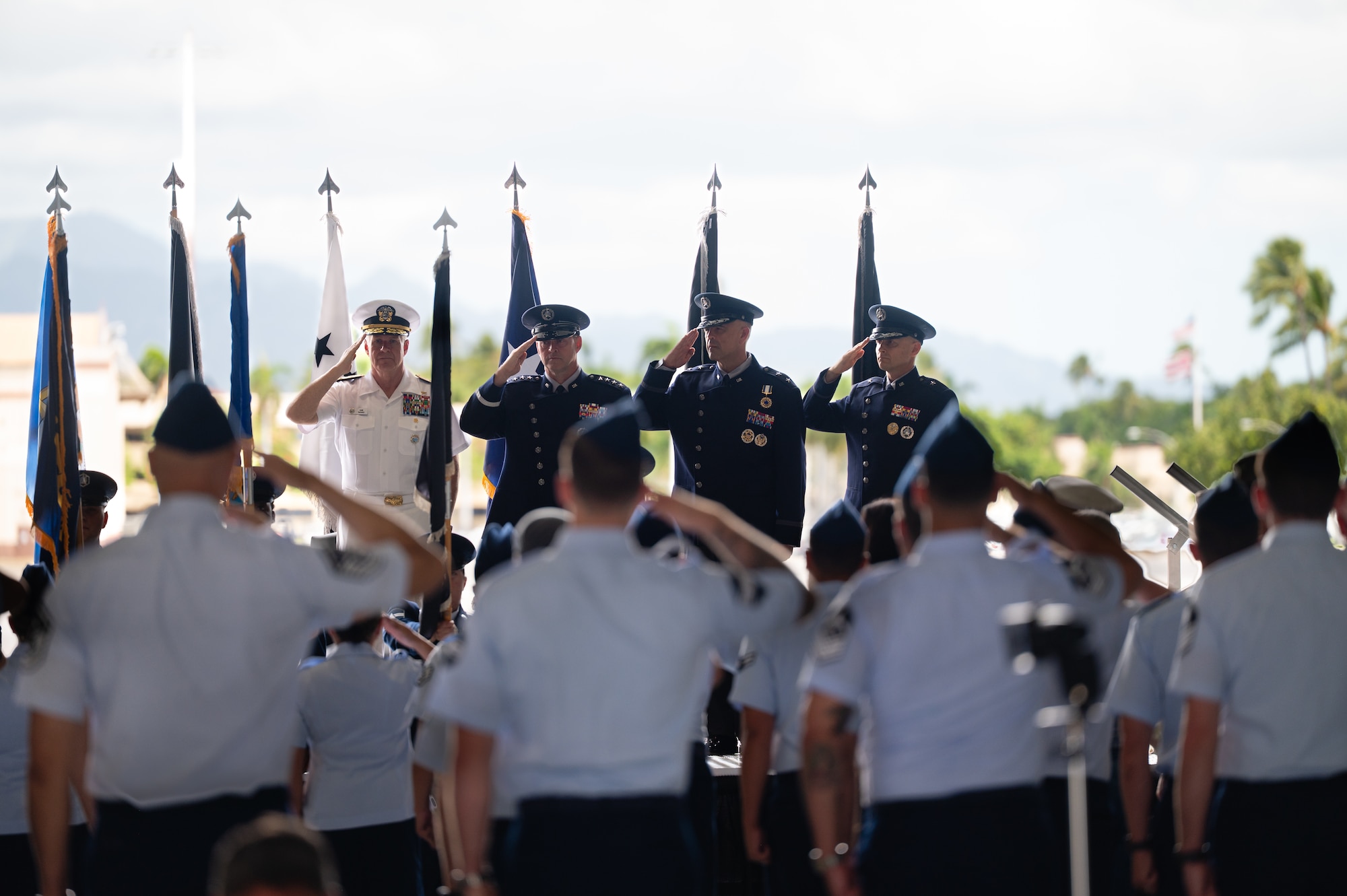Several uniformed men and women salute the American flag