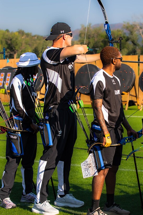 U.S. Army Staff Sgt. Coty Tuck, center, nocks an arrow in his bow and takes aim at his target during the archery event at the 2025 Department of Defense Warrior Games, Colorado Springs, Colorado, July 25, 2025.