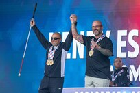 U.S. Army Retired Sgt. 1st Class Henry Escobedo, left, and Team Army coach Greg Quarles each receive two gold medals for cycling events during the 2025 Department of Defense Warrior Games at Warrior Games Plaza, Colorado Springs, Colorado, July 20, 2025.