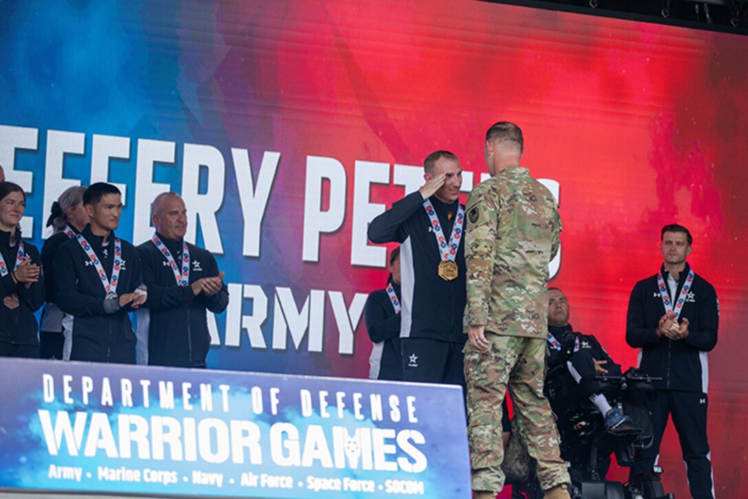 U.S. Army Sgt. 1st Class Jeffrey Peters salutes the Deputy Commanding General for Operations, U.S. Army Space and Missile Defense Command Brig. Gen. Donald K. Brooks after receiving two gold medals for the cycling event during the 2025 Department of Defense Warrior Games.
