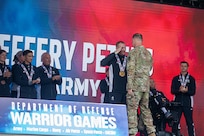 U.S. Army Sgt. 1st Class Jeffrey Peters salutes the Deputy Commanding General for Operations, U.S. Army Space and Missile Defense Command Brig. Gen. Donald K. Brooks after receiving two gold medals for the cycling event during the 2025 Department of Defense Warrior Games.