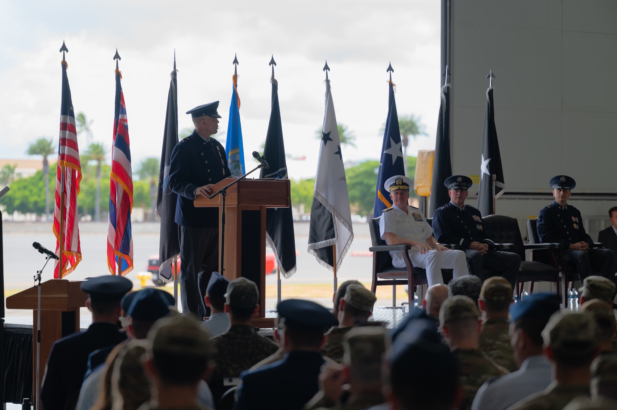 A man in uniform speak behind a podium to a crowd of people