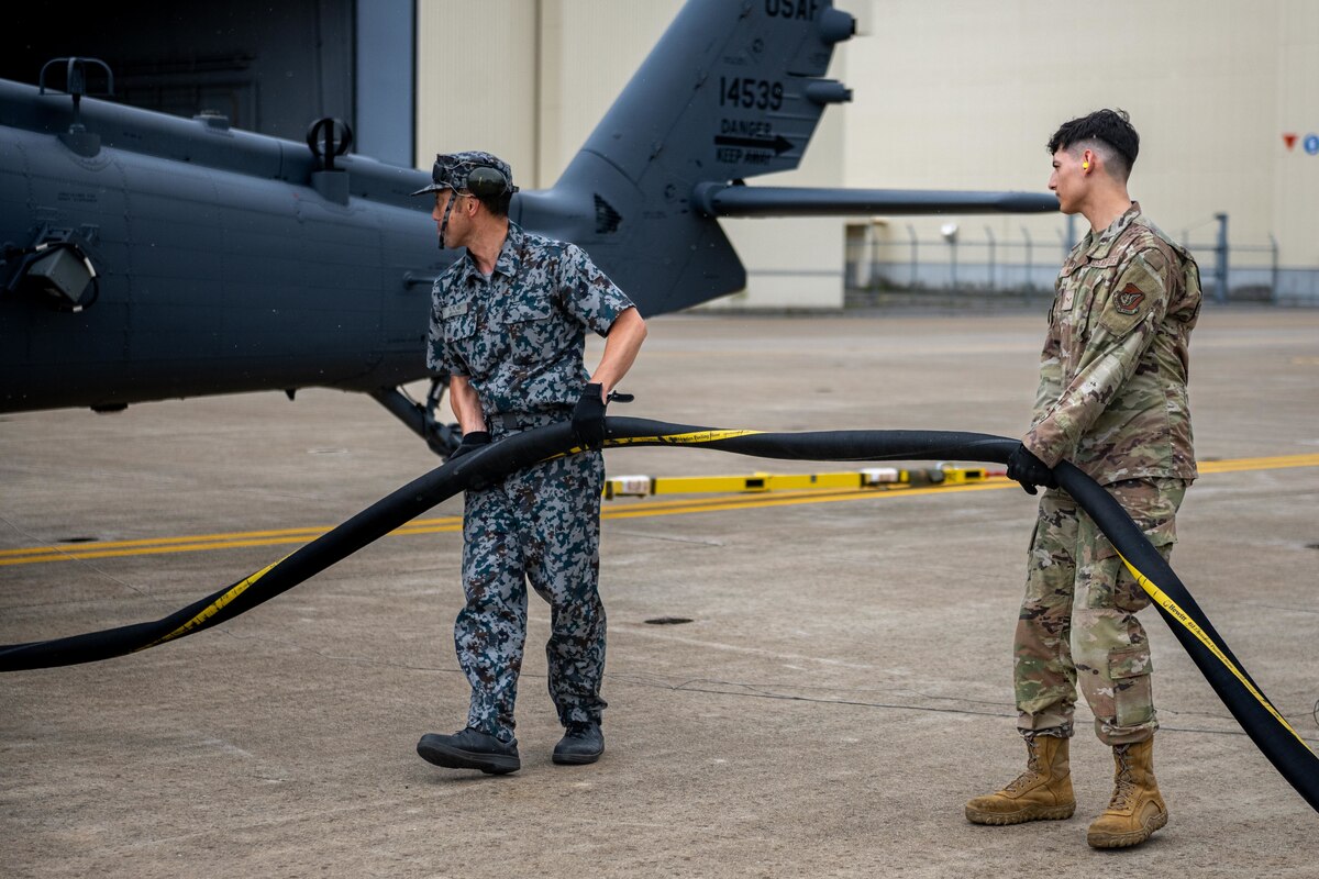 U.S. Air Force Airman 1st Class Andrew Mikel, right, 35th Logistic Readiness Squadron fuels distribution operator, and Japan Air Self-Defense Force Sgt. 1st Class Kasauki Okubo, 3rd Air Wing petroleum, oil, and lubricant technician, holds a fuel hose before fueling a U.S. Air Force HH-60 Pave Hawk during exercise Resolute Force Pacific (REFORPAC) 2025.