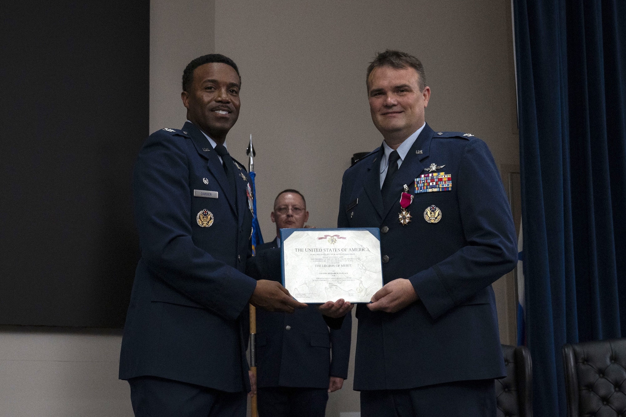 Col. Richard Wallace receives the Legion of Merit during the 960th Cyberspace Operations Group change of command ceremony at JBSA-Lackland, Texas on July 12, 2025. The ceremony was held prior to the 960th Cyberspace Wing change of command. Col. Wallace and Col. Silas Darden present the certificate for a photo. (US Air Force photo by TSgt Melissa Estevez)