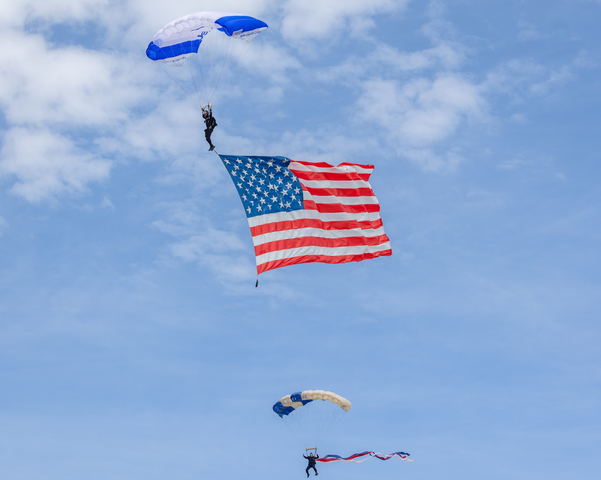 Two men with parachutes and American flag in sky.