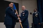 Col. Joshua Garrison assumes command of the 960th Cyberspace Wing and receives the wing guidon from 10th Air Force commander Brig. Gen. Kevin Merrill during the 960th Cyberspace Wing change of command ceremony at JBSA-Lackland, Texas on July 12, 2025. (US Air Force photo by TSgt Melissa Estevez)