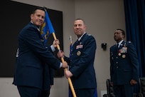 Col. Joshua Garrison assumes command of the 960th Cyberspace Wing and receives the wing guidon from 10th Air Force commander Brig. Gen. Kevin Merrill during the 960th Cyberspace Wing change of command ceremony at JBSA-Lackland, Texas on July 12, 2025. (US Air Force photo by TSgt Melissa Estevez)