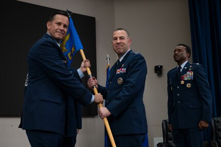 Col. Joshua Garrison assumes command of the 960th Cyberspace Wing and receives the wing guidon from 10th Air Force commander Brig. Gen. Kevin Merrill during the 960th Cyberspace Wing change of command ceremony at JBSA-Lackland, Texas on July 12, 2025. (US Air Force photo by TSgt Melissa Estevez)