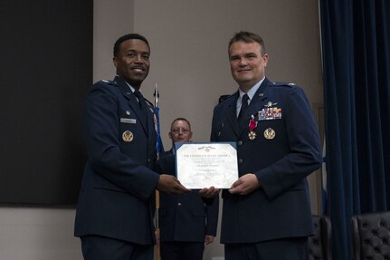 Col. Richard Wallace receives the Legion of Merit during the 960th Cyberspace Operations Group change of command ceremony at JBSA-Lackland, Texas on July 12, 2025. The ceremony was held prior to the 960th Cyberspace Wing change of command. Col. Wallace and Col. Silas Darden present the certificate for a photo. (US Air Force photo by TSgt Melissa Estevez)
