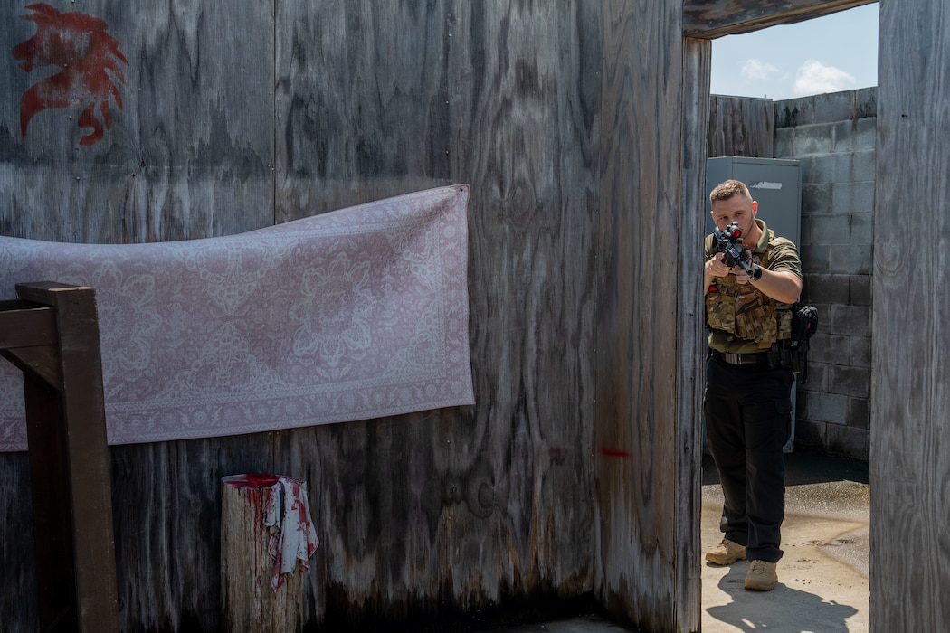 Man clears a room while holding up a fake gun while conducting a fugitive apprehension exercise