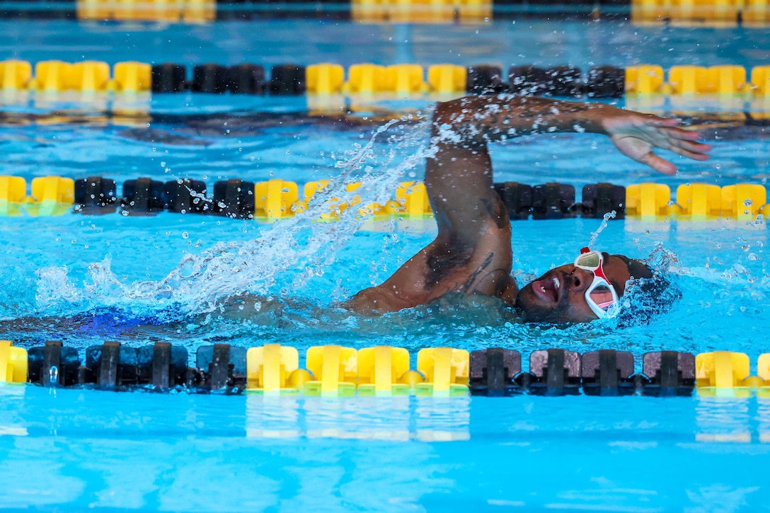 A close-up of a soldier taking a breath while swimming in a lap pool.