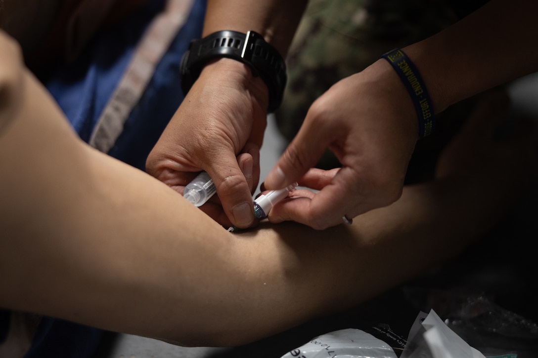 U.S. Navy Lt. Cmdr. Carolan Whitney, a medical officer with 2nd Medical Battalion, 2nd Marine Logistics Group, performs medical care on a simulated casualty during a Tier IV Tactical Combat Casualty Care Course at the Battle Skills Training School, Marine Corps Base Camp Lejeune, North Carolina, July 21, 2025.This was the first ever Tier IV TCCC hosted by a Marine Corps command and the first course executed by U.S. Navy personnel on the East Coast. The course trains select military service members to become proficient combat paramedics capable of providing advanced casualty care at the point of injury on the battlefield and in austere environments.