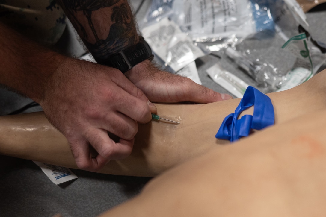 U.S. Navy Lt. Levi Boland, a medical officer with 2nd Medical Battalion, 2nd Marine Logistics Group, applies an IV on a simulated casualty during a Tier IV Tactical Combat Casualty Care Course at the Battle Skills Training School, Marine Corps Base Camp Lejeune, North Carolina, July 21, 2025. This was the first ever Tier IV TCCC hosted by a Marine Corps command and the first course executed by U.S. Navy personnel on the East Coast. The course trains select military service members to become proficient combat paramedics capable of providing advanced casualty care at the point of injury on the battlefield and in austere environments.