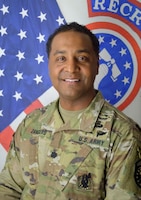 Smiling Army Soldier poses in front of the American and United States Army Recruiting Command flags