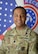 Smiling Army Soldier poses in front of the American and United States Army Recruiting Command flags
