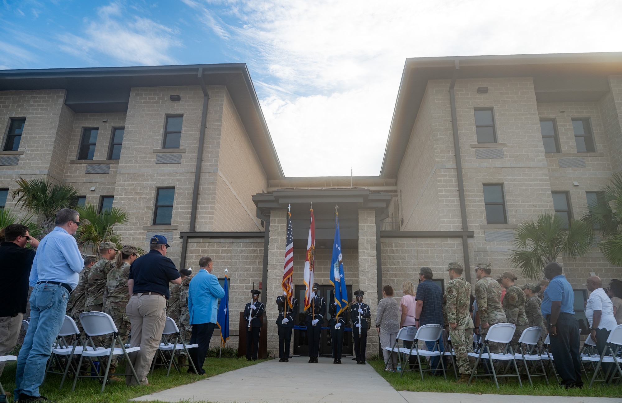 Guests stand and salute the U.S. flag in front of a new dormitory.