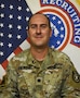 Soldier smiles while posing in front of American flag and United States Army Recruiting Command flag.