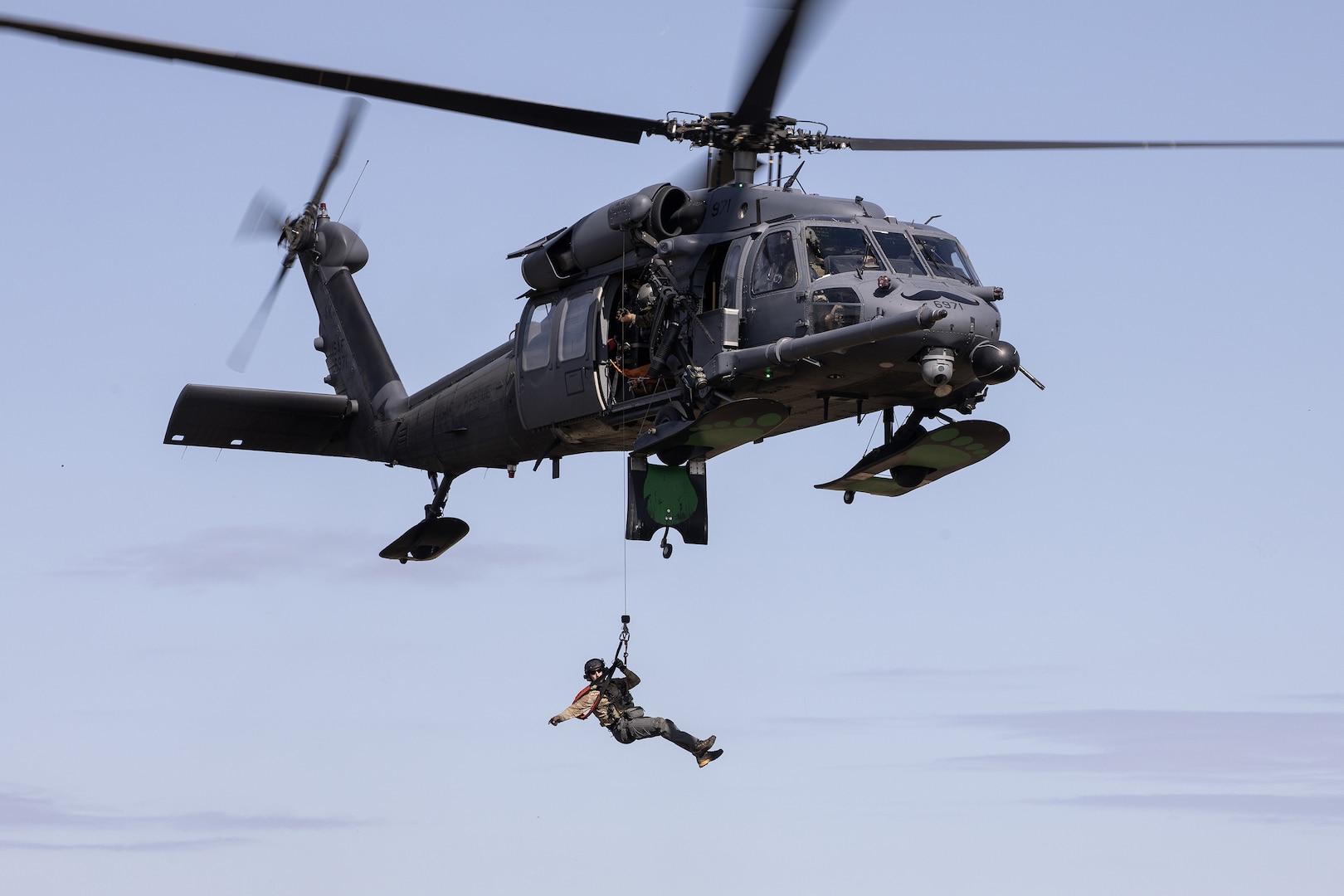 Alaska Air National Guard HH-60G Pave Hawk aviators and Guardian Angels, assigned to the 210th and 212th Rescue Squadrons, respectively, conduct a hoist rescue demonstration while participating in a multi-agency hoist symposium at Bryant Army Airfield on Joint Base Elmendorf-Richardson, Alaska, July 22, 2025.
