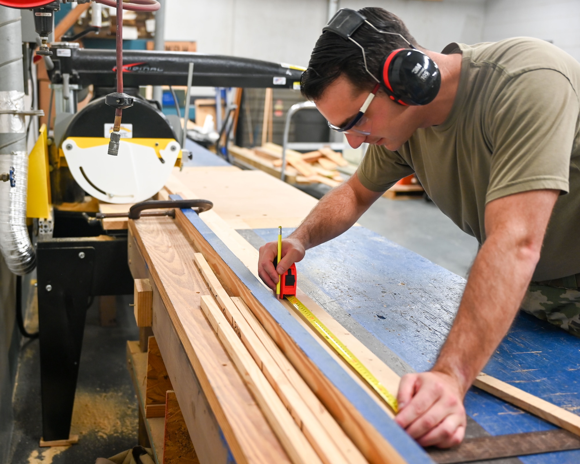 U.S. Air Force Staff Sgt. John Cardoza, 42d Logistics Readiness Squadron noncommissioned officer in charge of outbound cargo, measures wood to construct packaging for a critical asset in the Air Force supply system at Maxwell Air Force Base, Alabama, July 23, 2025. Often times due to wear and tear and or due to time, some wooden containers need to be built or fix to continue the life cycle of protecting equipment. The 42nd LRS uses various saws to use to construct and fabricate crates to safeguard critical items in transportation. (U.S. Air Force Photo by Senior Airman Tanner Doerr)
