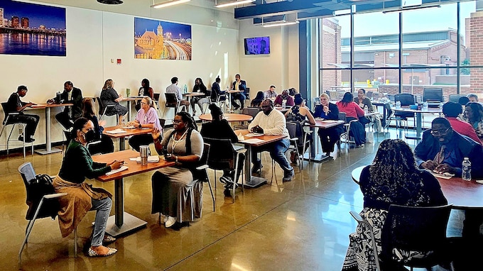 There is a group of tables with people seating on two sides.