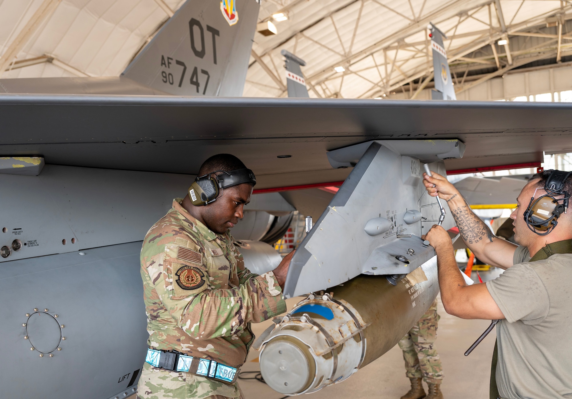 Load crew members attach a GBU-38 Joint Direct Attack Munition on an F-16 Fighting Falcon.