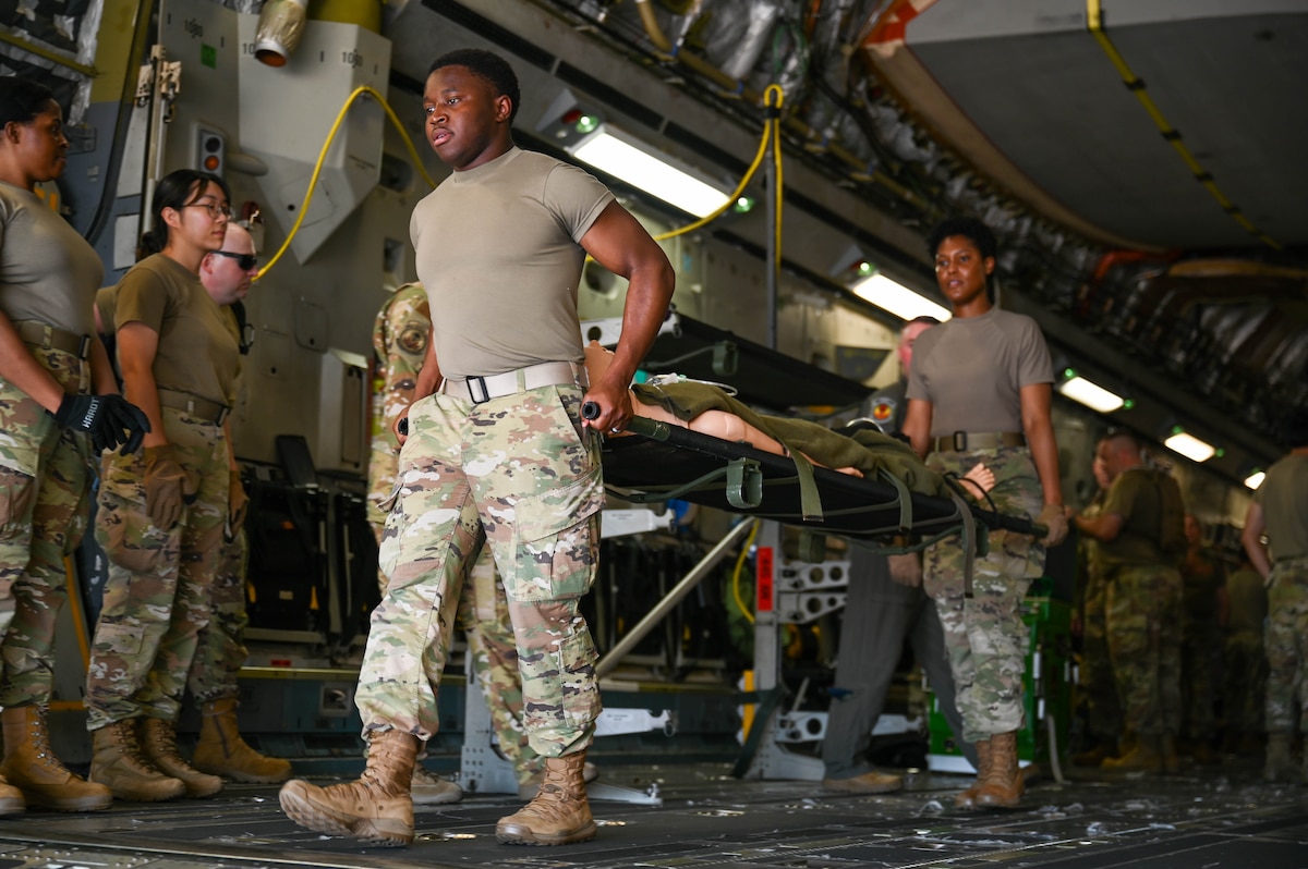 Airmen transport a simulated patient on a stretcher aboard a C17 Globemaster III.