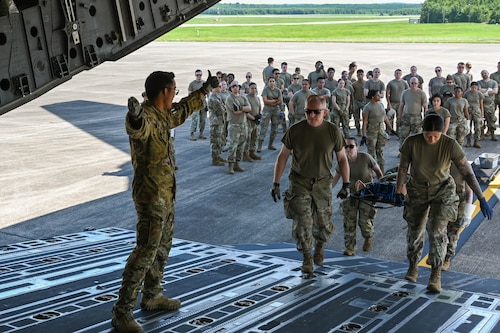 Airmen carry a stretcher up the ramp of a C17 Globemaster III.