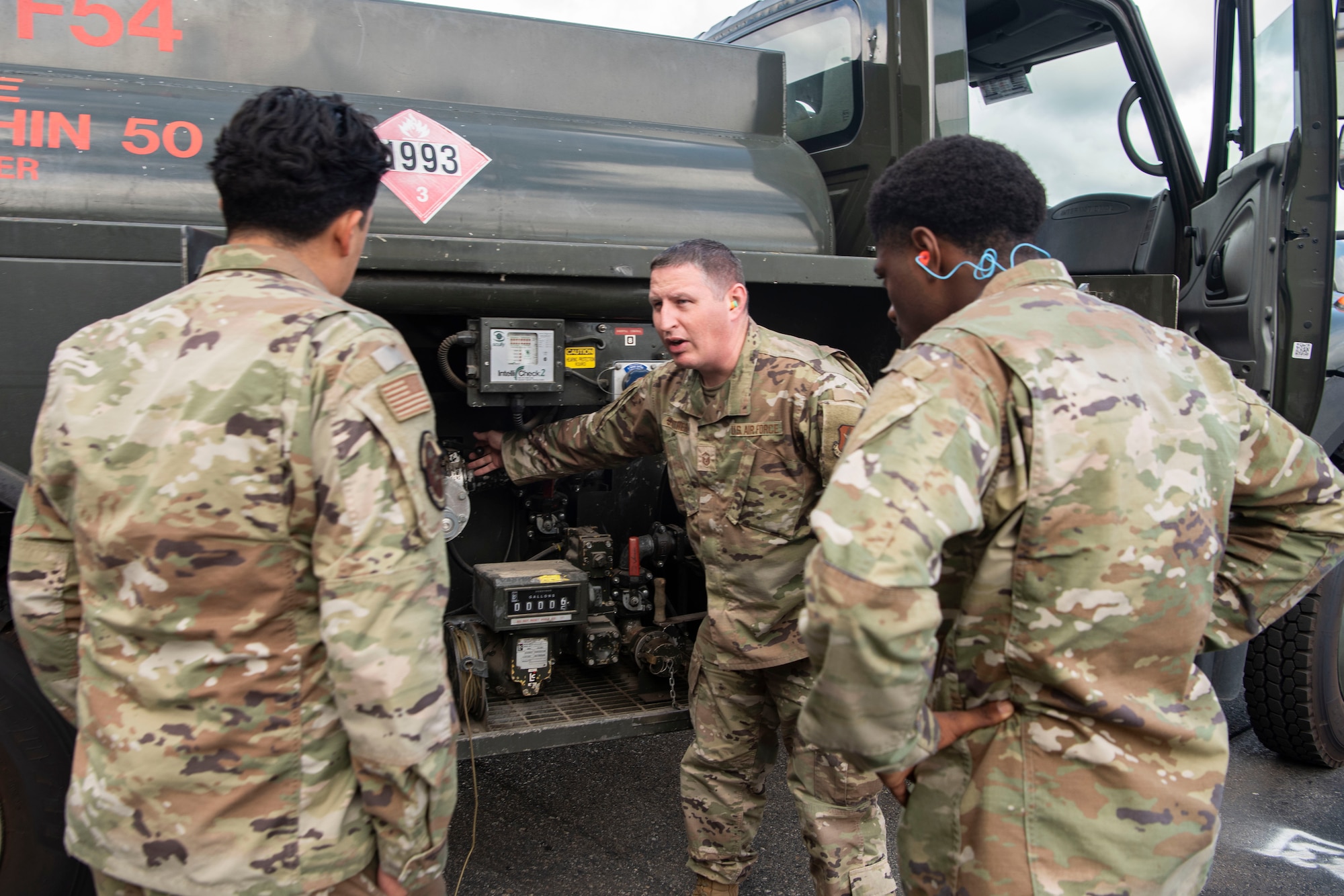 U.S. Air Force Master Sgt. Tom Struthers, 927th Logistics Readiness Squadron fuels operations NCO in charge, center, teaches Senior Airman Amzy Zalvia, 433rd LRS fuels specialist, left, and Senior Airman Jaylon Holliday, 433rd LRS fuels specialist, about diesel refueling operations during Red Flag Alaska 25-3 at Eielson Air Force Base, Alaska, July 25, 2025.