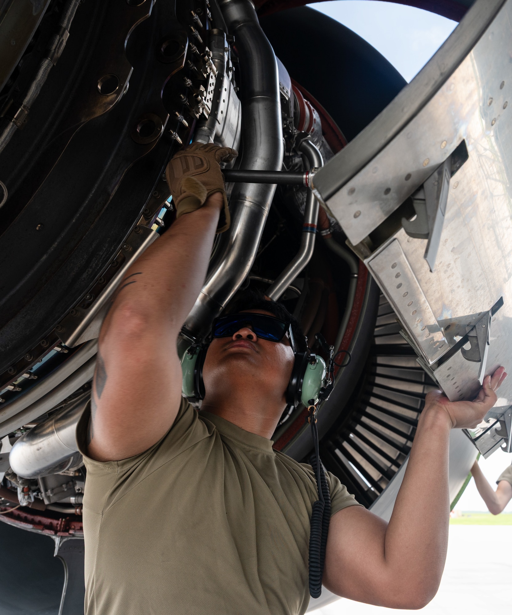U.S. Air Force Senior Airman Saege Ayala, 22nd Aircraft Maintenance Squadron electrical and environmental technician, closes the cover of a KC-46A Pegasus engine after conducting repairs during the Air Force's 2025 Department-Level Exercise series at Andersen Air Force Base, Guam, July 15, 2025. The DLE strengthens and demonstrates the U.S. Air Force’s ability to reach theater at speed and scale, sustain operations, and rapidly pivot to any theater of operation at a moment’s notice while maintaining the strategic initiative. The DLE series encompasses all branches of the Department of Defense, along with Allies and partners, employing more than 400 joint and coalition aircraft and more than 12,000 personnel across more than 50 locations across 3,000 miles. (U.S. Air Force photo by Staff Sgt. Tryphena Mayhugh)