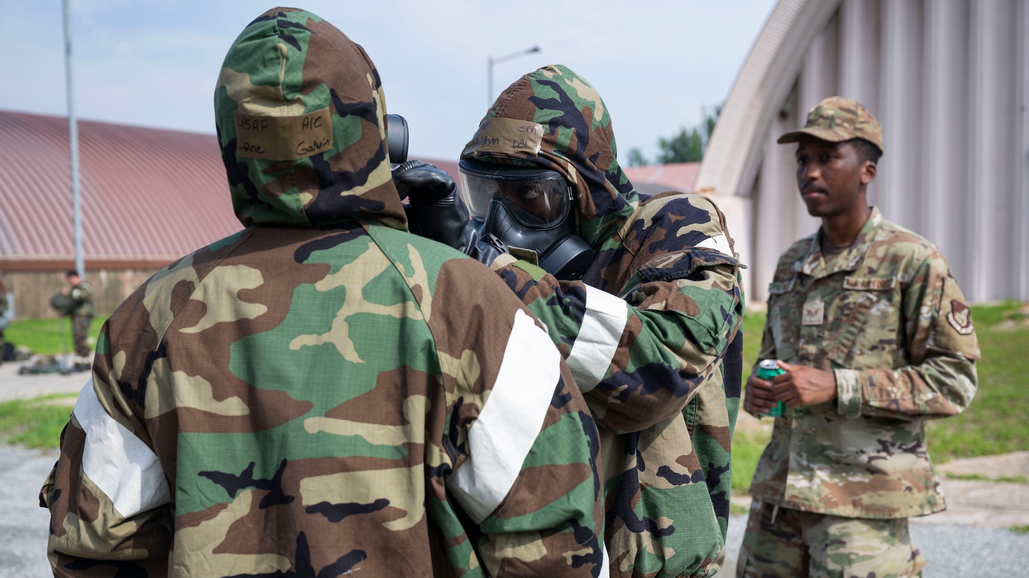 U.S. Air Force Senior Airman Jonathan Bell, center, 51st Force Support Squadron customer support technician, conducts a buddy-check during the ability to survive and operate training at Osan Air Base, Republic of Korea, July 24, 2025. During ATSO training, Airmen refreshed their ability to quickly assemble their mission-oriented protective posture gear to ensure survival in a contingency environment. (U.S. Air Force photo by Senior Airman Rome Bowermaster)