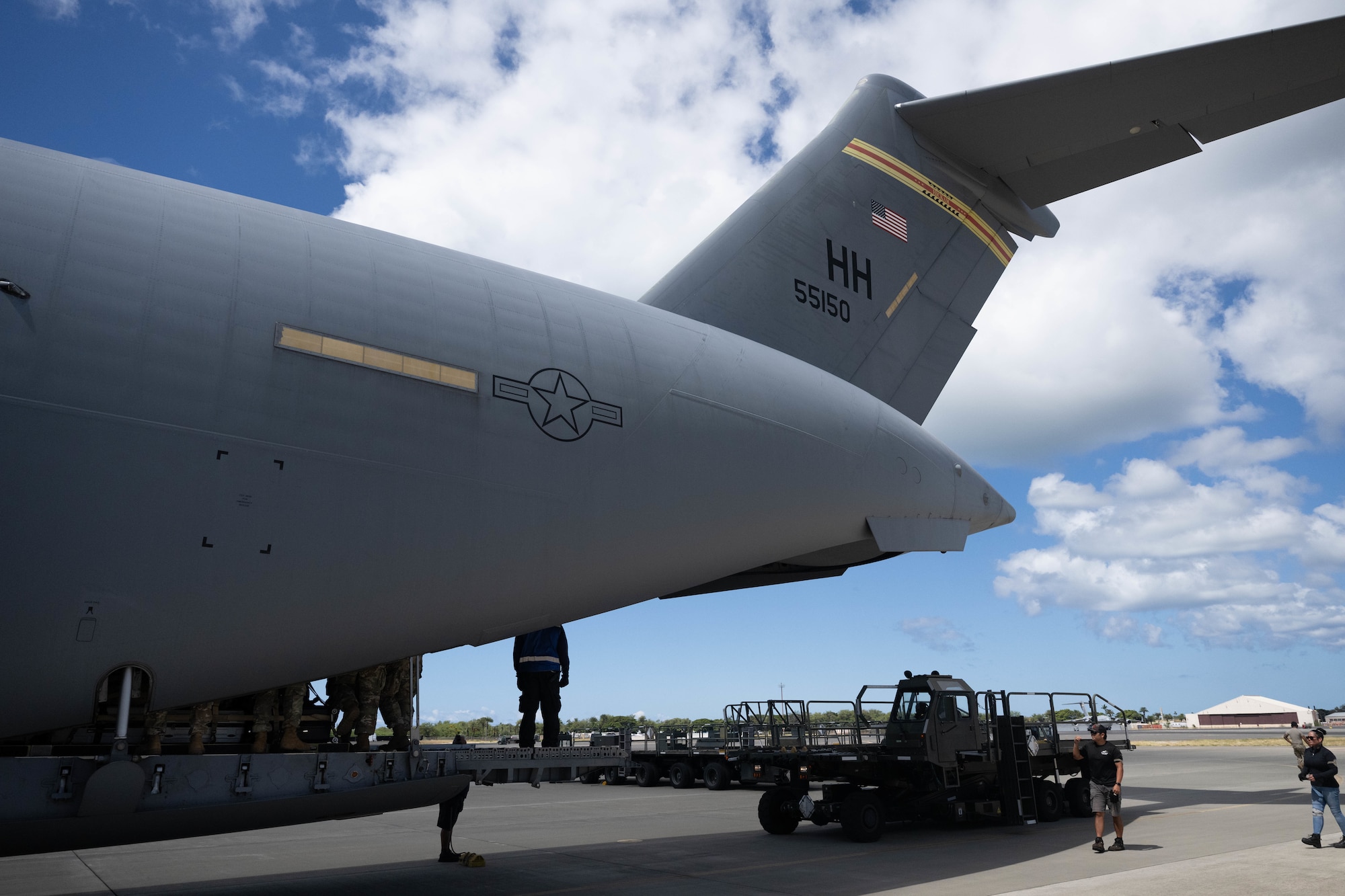 Airmen under the tail of a C-17, unloading cargo.