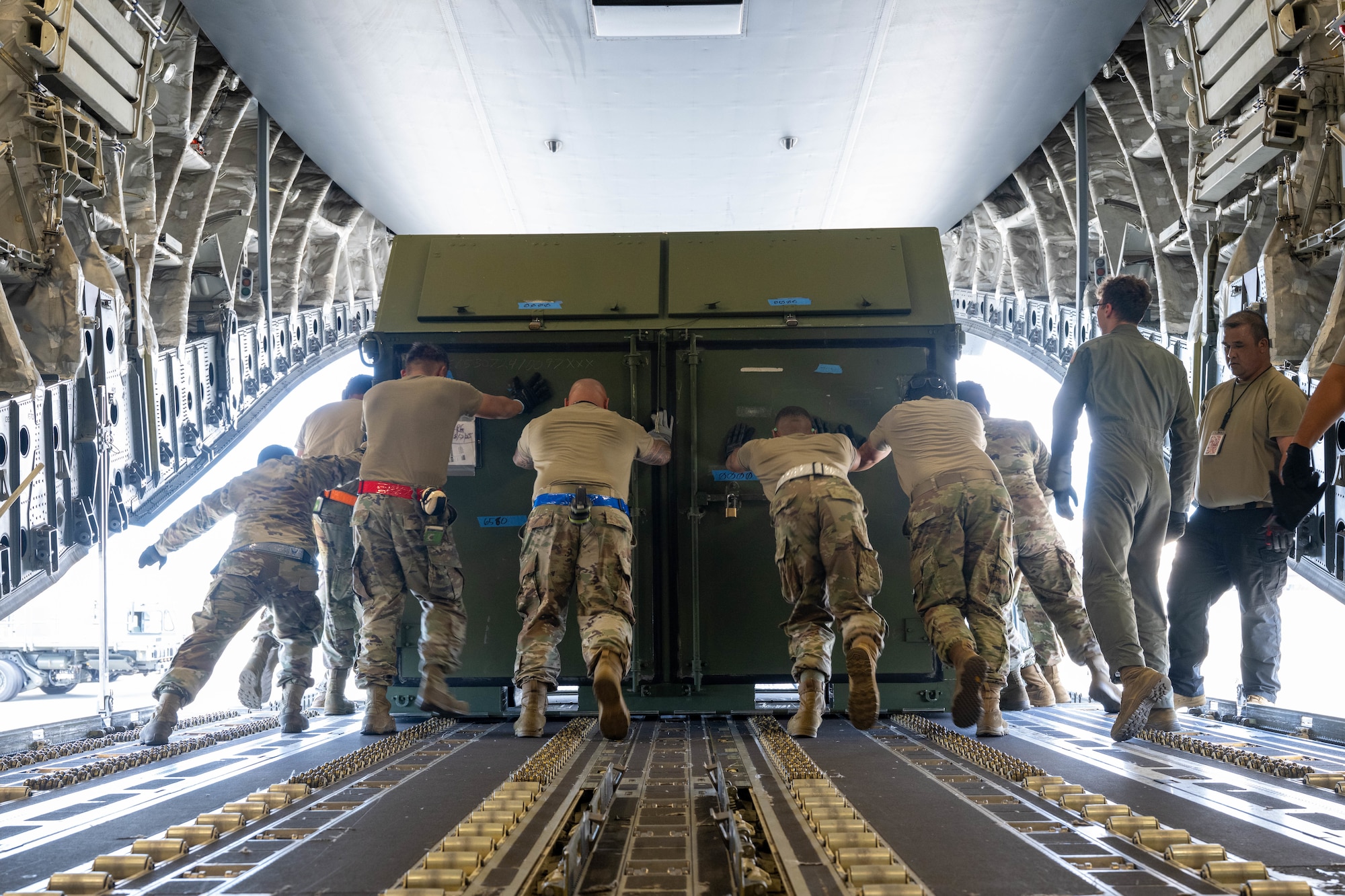 Airmen pushing cargo outside of a C-17.
