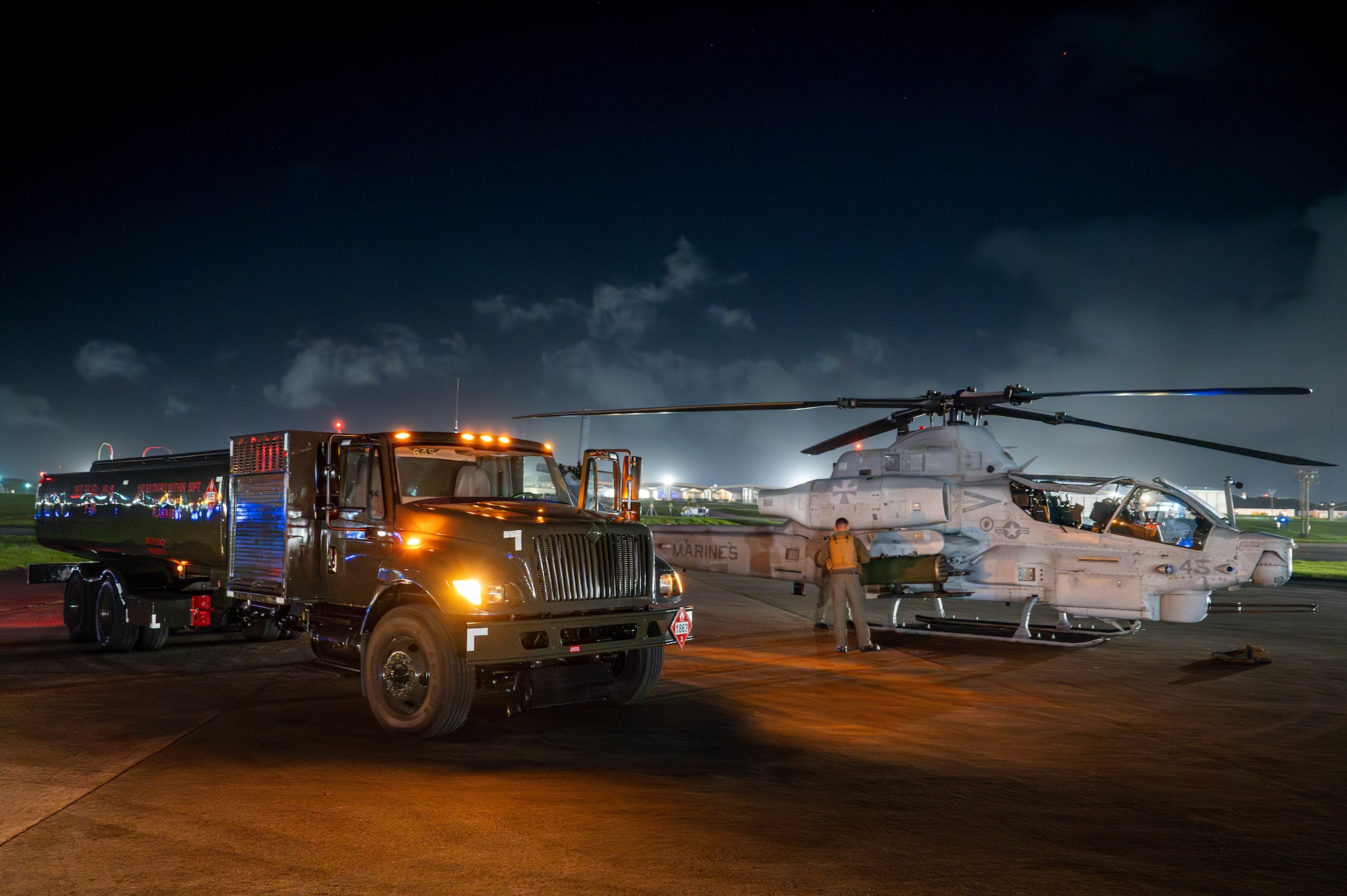 An R-11 refuel truck assigned to the 18th Logistics Readiness Squadron, prepares to depart after refueling an AH-1 Cobra assigned to Marine Light Attack Helicopter Squadron 169.