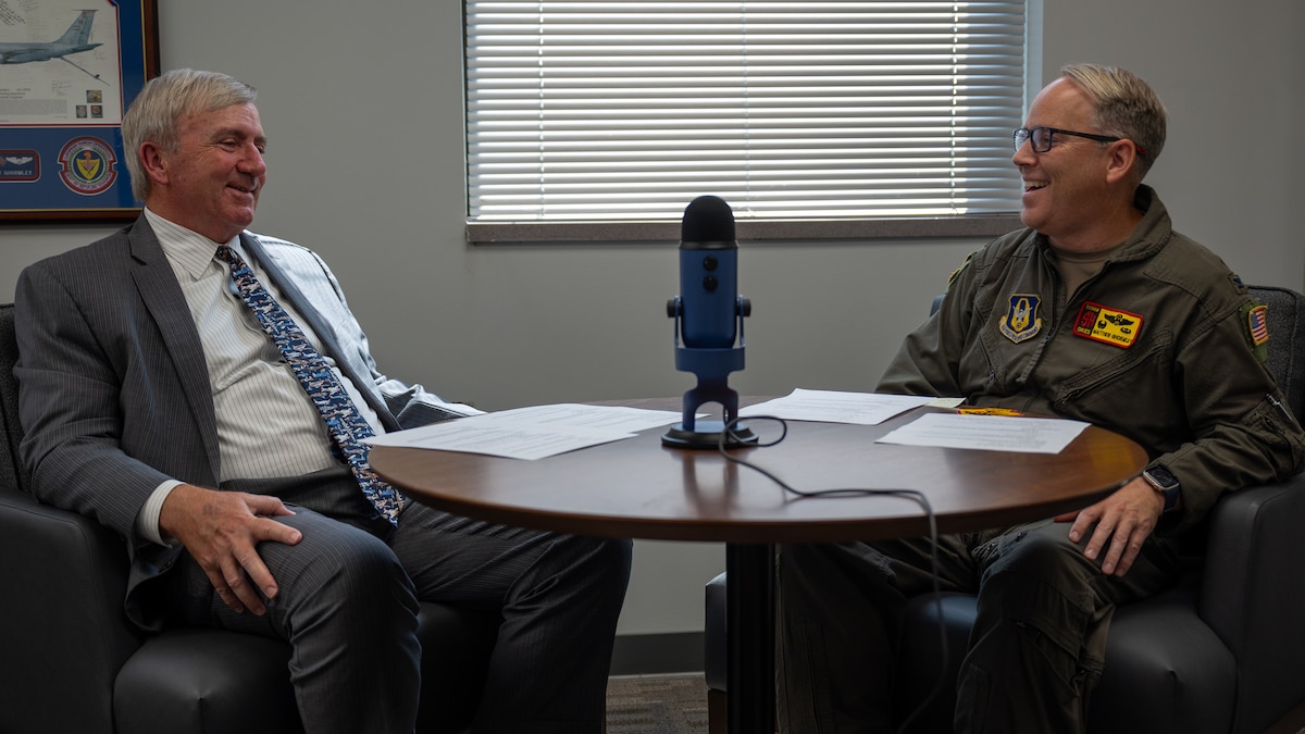 two men speak at table