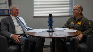 two men speak at table