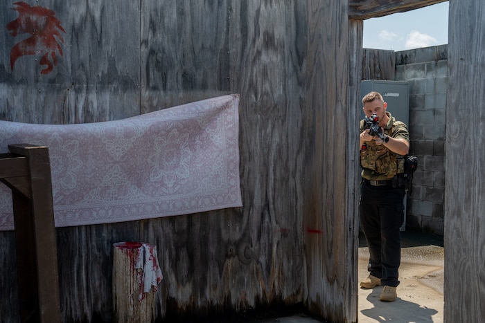 Man clears a room while holding up a fake gun while conducting a fugitive apprehension exercise